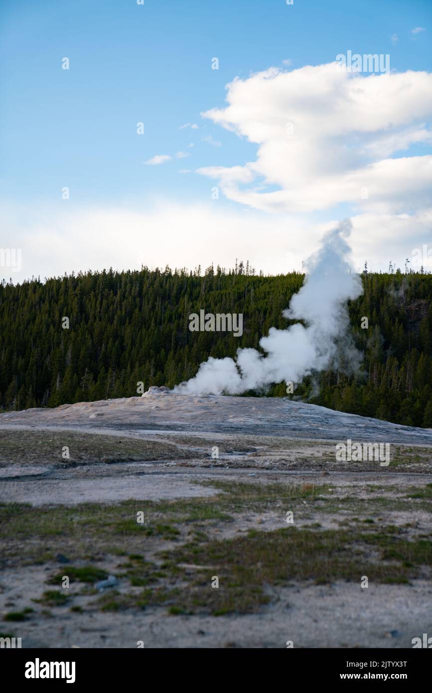 a vertical shot of a volcanic steam coming out of geyser hole in ground. Stock Photo