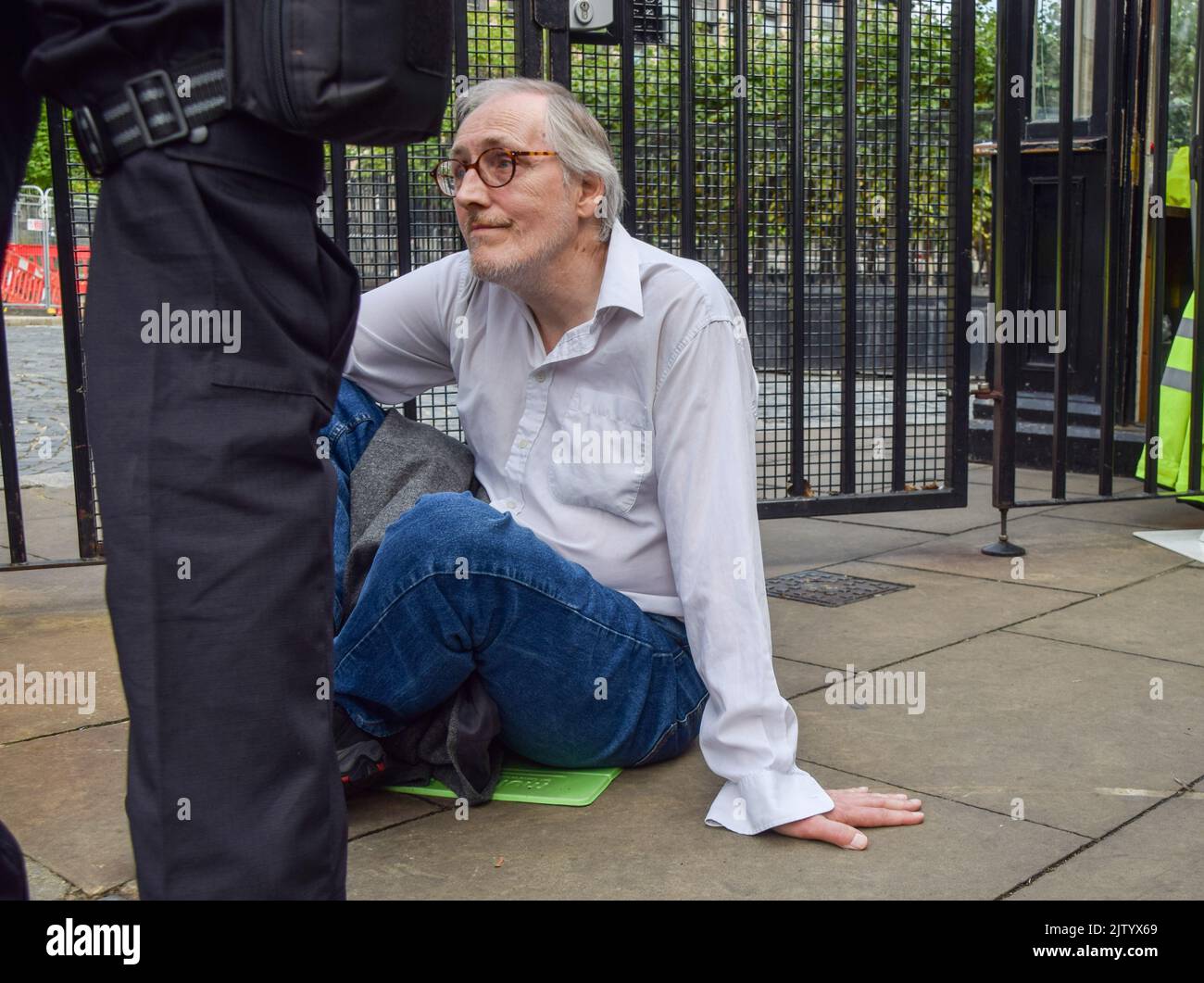 London, UK. 2nd September 2022. An activist sits with his hand glued to the ground at the Parliament gates. Extinction Rebellion protesters glued themselves inside the Parliament while others locked and glued themselves outside, demanding a Citizens' Assembly. Credit: Vuk Valcic/Alamy Live News Stock Photo