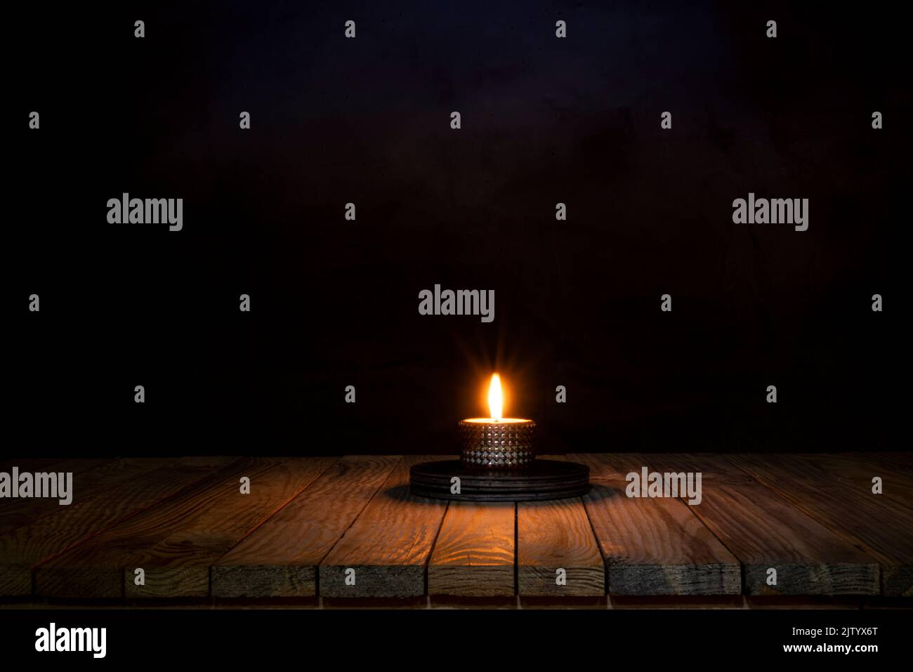 Candle light spreading on wooden table surface. Stock Photo