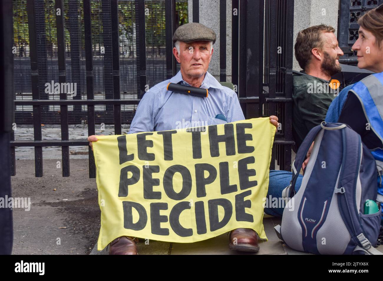 London, UK. 2nd September 2022. An activist sits with his neck locked to the fence outside Parliament. Extinction Rebellion protesters glued themselves inside the Parliament while others locked and glued themselves outside, demanding a Citizens' Assembly. Credit: Vuk Valcic/Alamy Live News Stock Photo