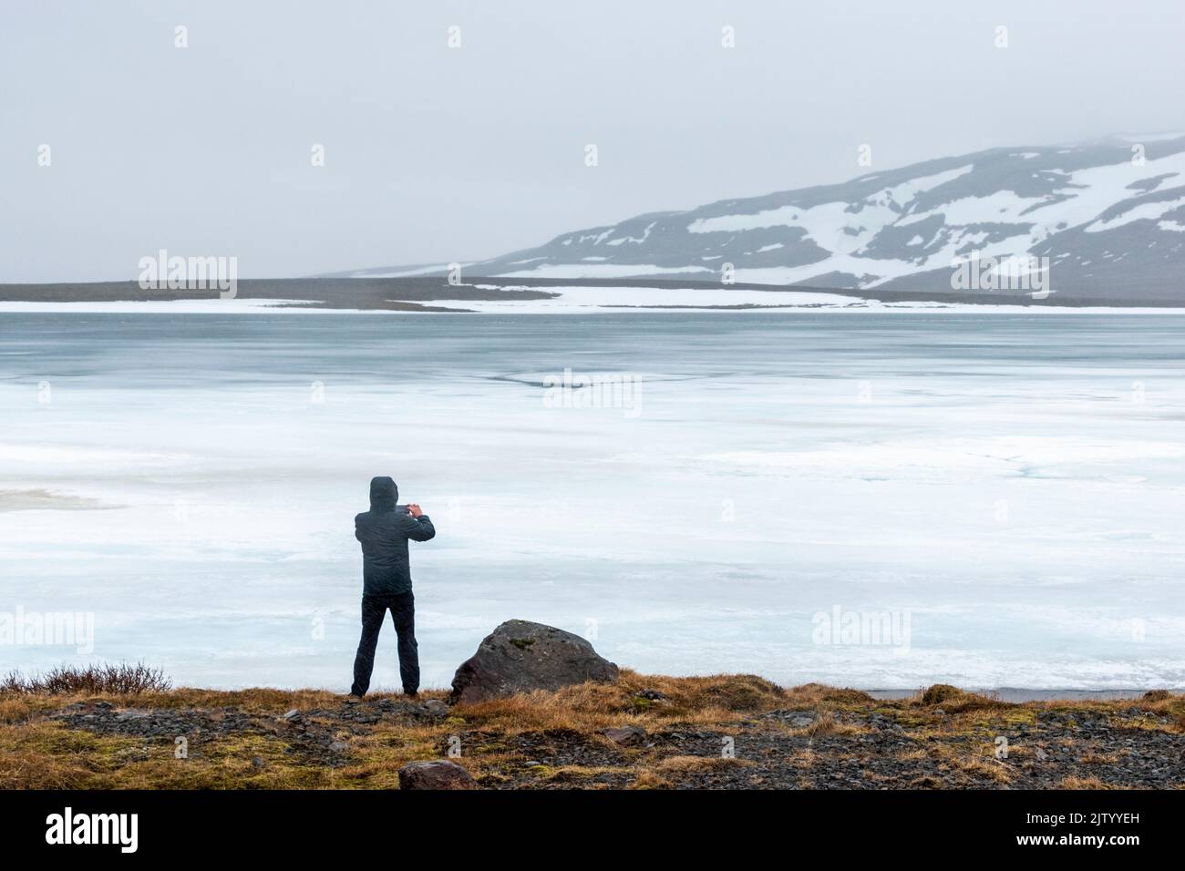 Man stopped by the side of a frozen lake in Iceland. Stock Photo