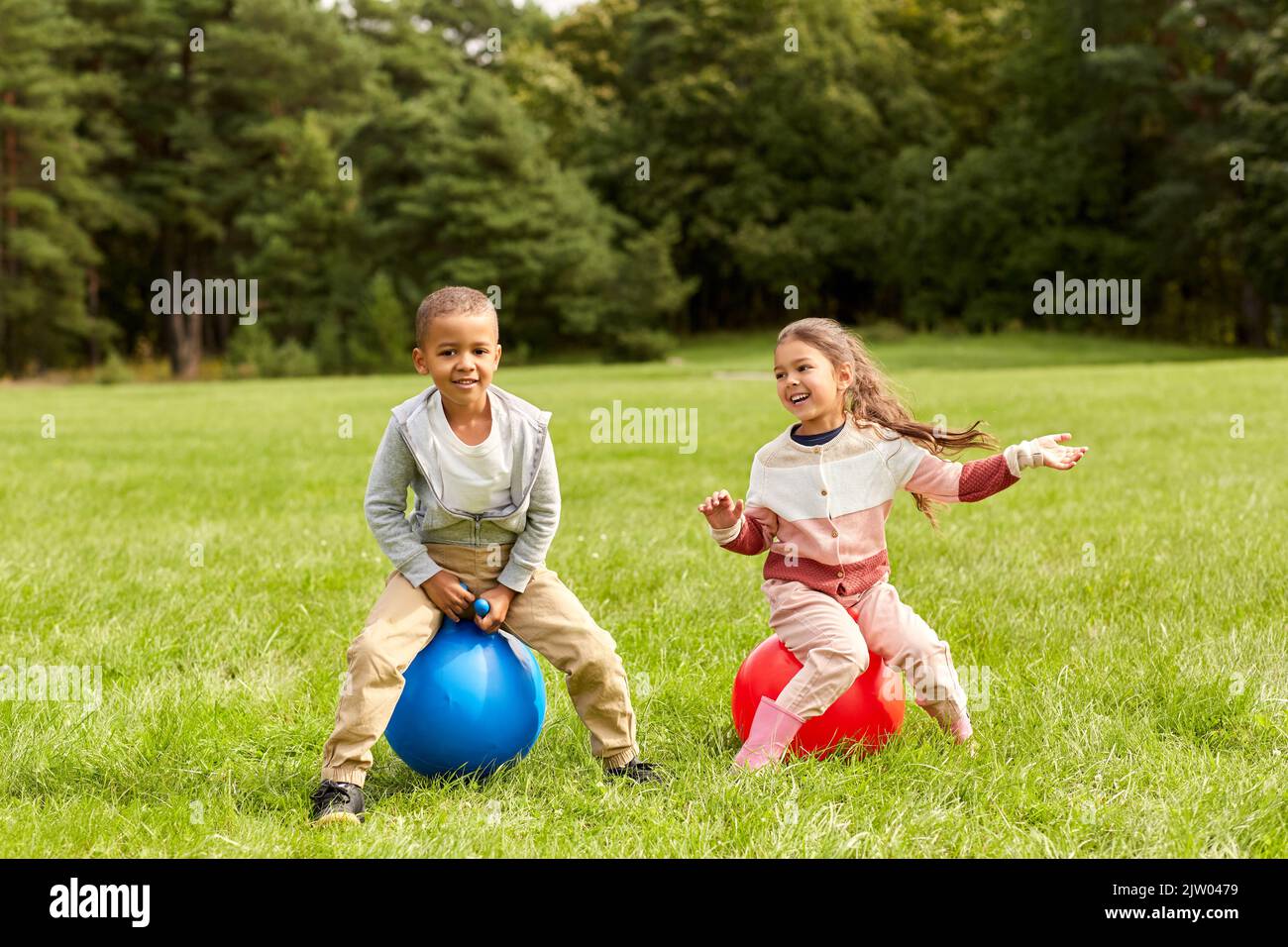 happy children bouncing on hopper balls at park Stock Photo Alamy