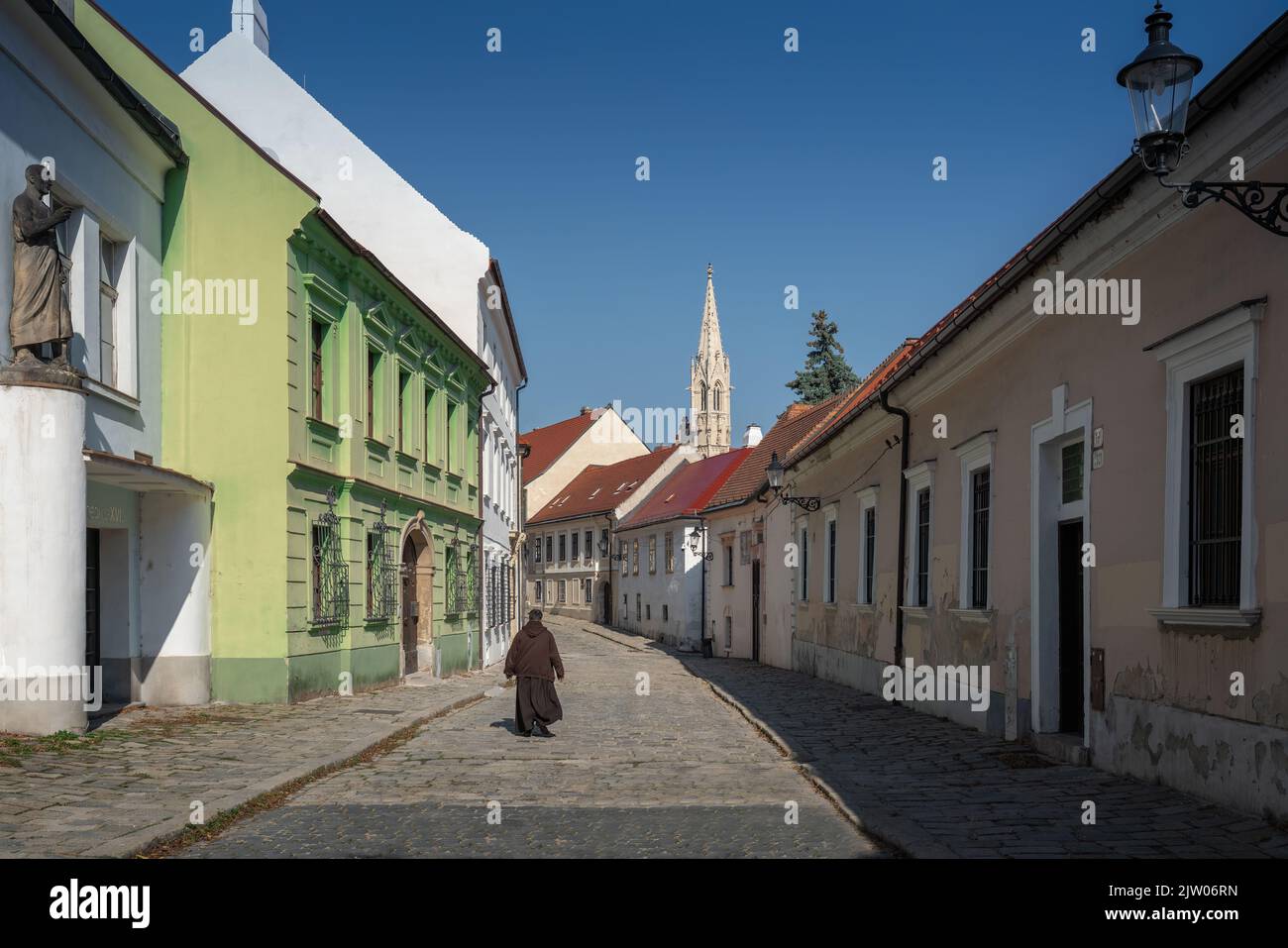 Monk on a street in Bratislava Old Town with Clarissine Church Tower on background - Bratislava, Slovakia Stock Photo
