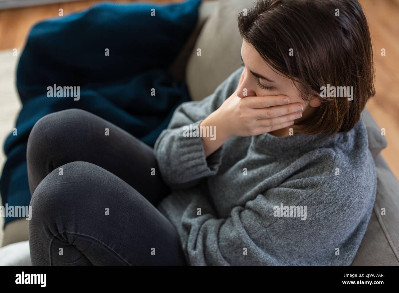 stressed woman sitting on sofa at home Stock Photo - Alamy