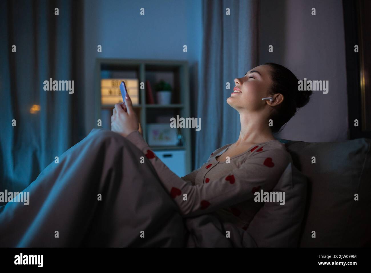 happy teenage girl with phone and earphones in bed Stock Photo - Alamy
