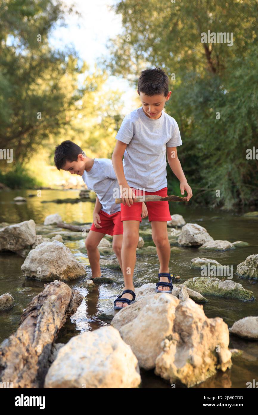 two children play among the stones of the river in summertime Stock ...