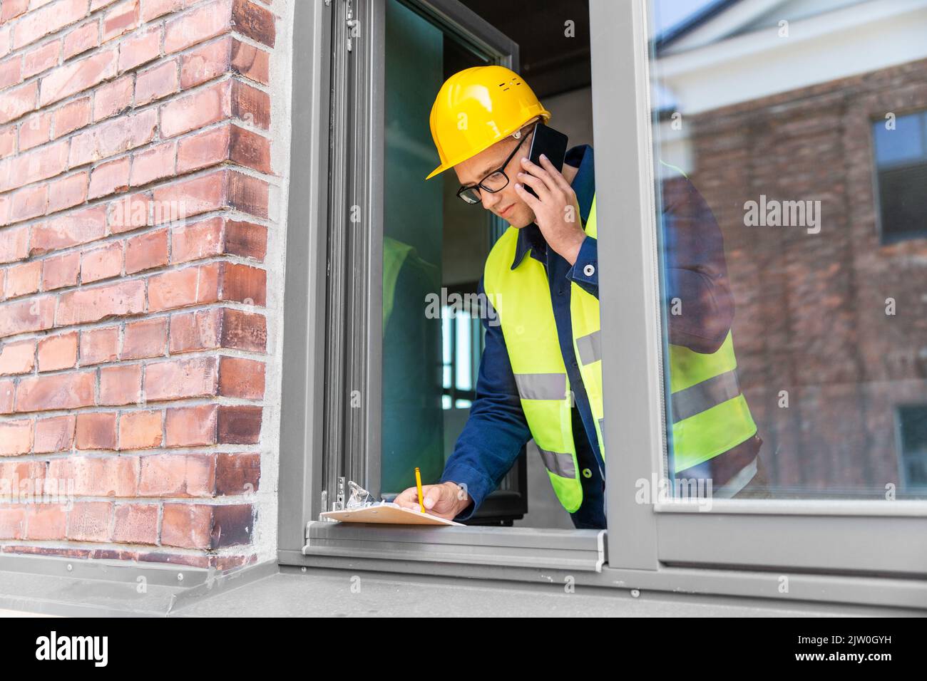 builder with clipboard and calling on smartphone Stock Photo