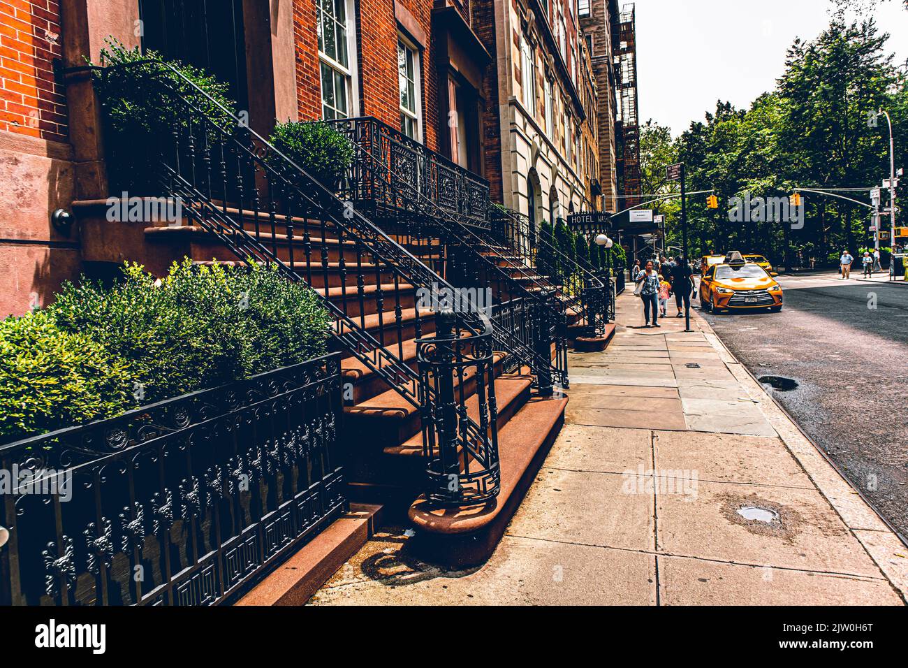 People walking on a New York City sidewalk along yellow taxi, New York City, New York State Stock Photo