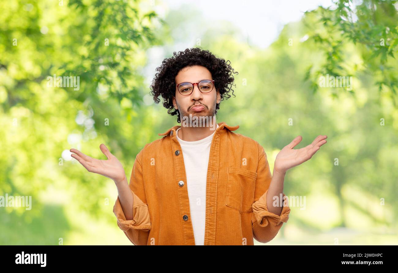 confused man shrugging on natural background Stock Photo
