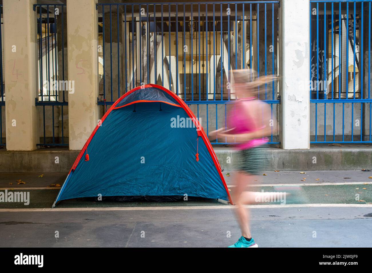London, UK. 31 Oct, 2022. A female jogger running past a rough sleeper's tent in London. Stock Photo