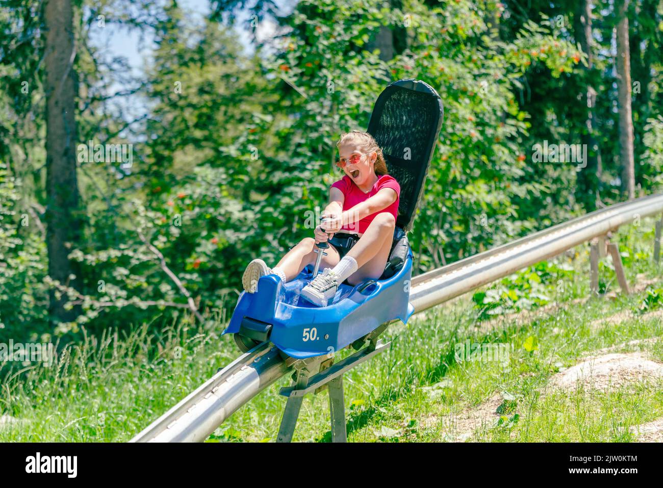 Teenage girl screams going down a mountain roller coaster Stock Photo