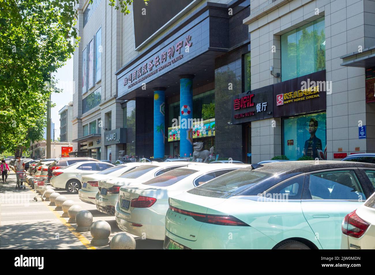Modern cars parked outside a shopping mall entrance in the downtown district. Stock Photo
