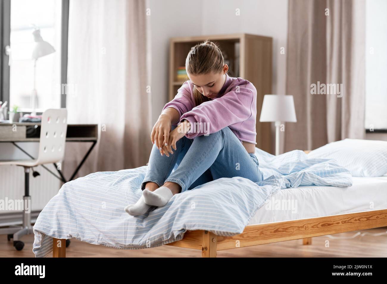 sad girl sitting on bed at home Stock Photo - Alamy