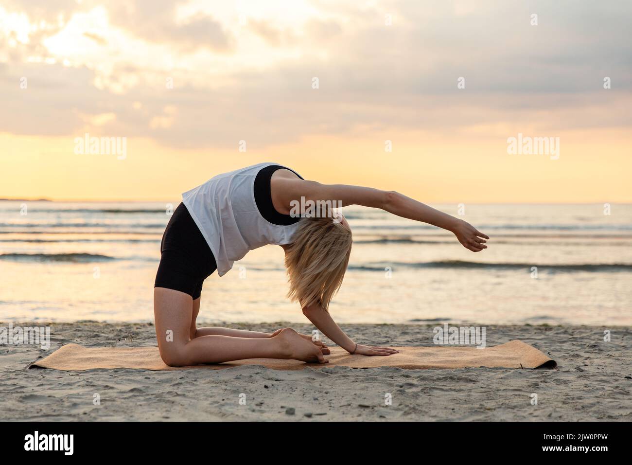 woman doing yoga camel pose on beach Stock Photo