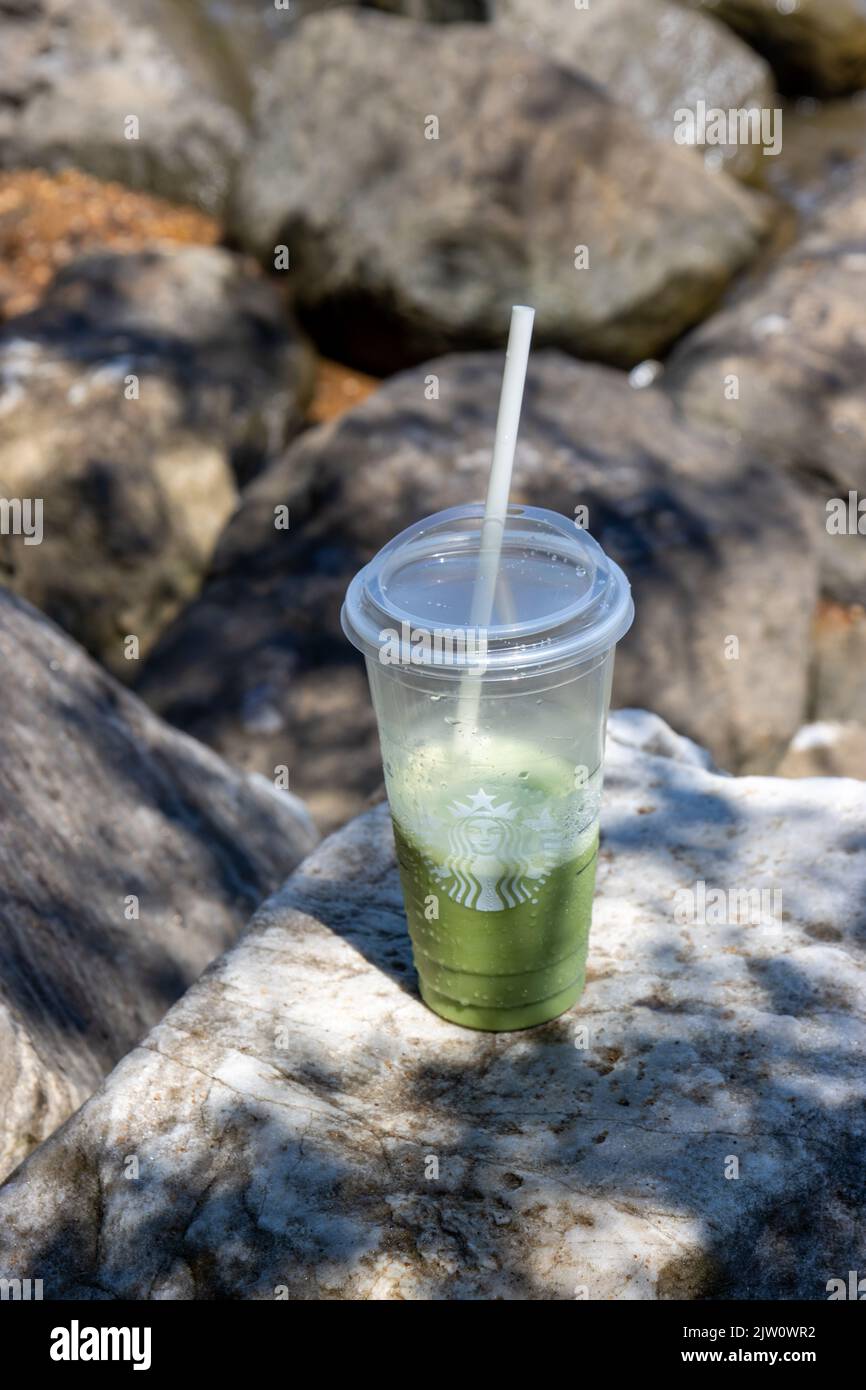 Starbucks Matcha Creme Frappuccino on a rock by the beach Stock Photo