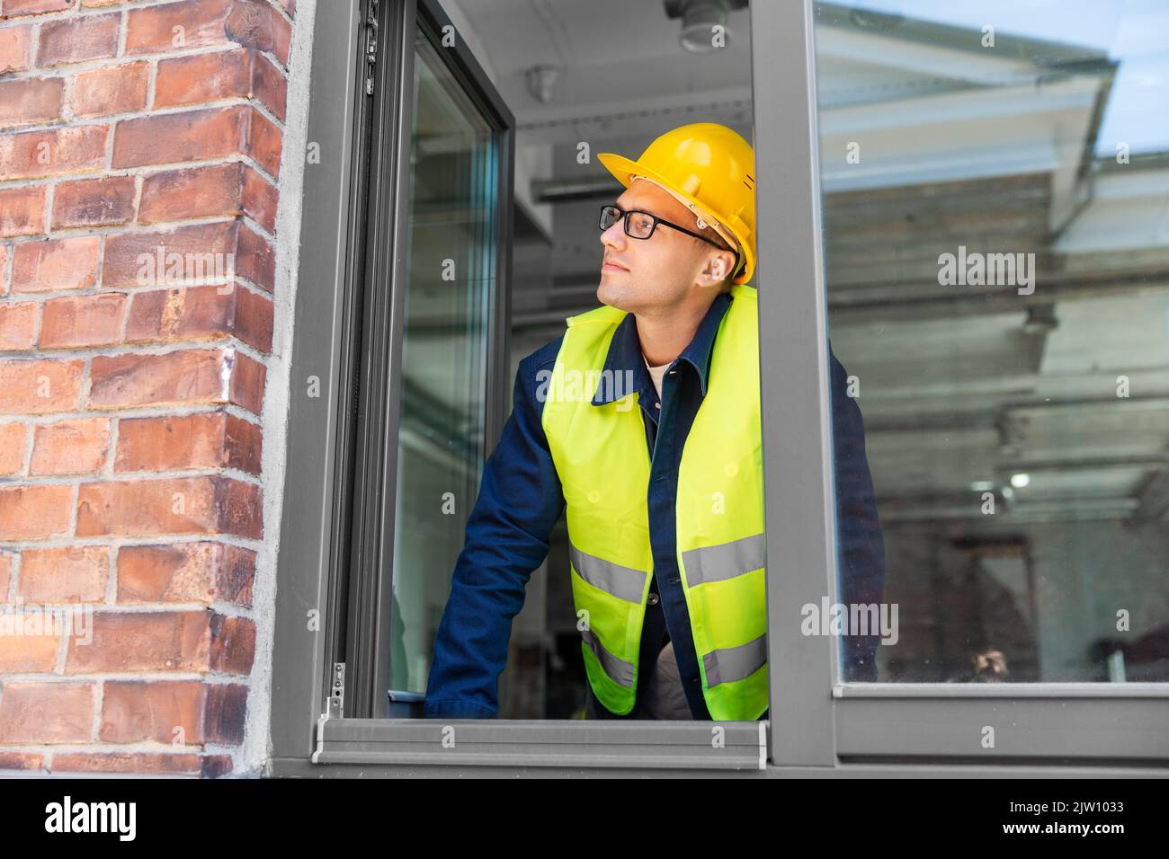 male builder in helmet looking out window Stock Photo