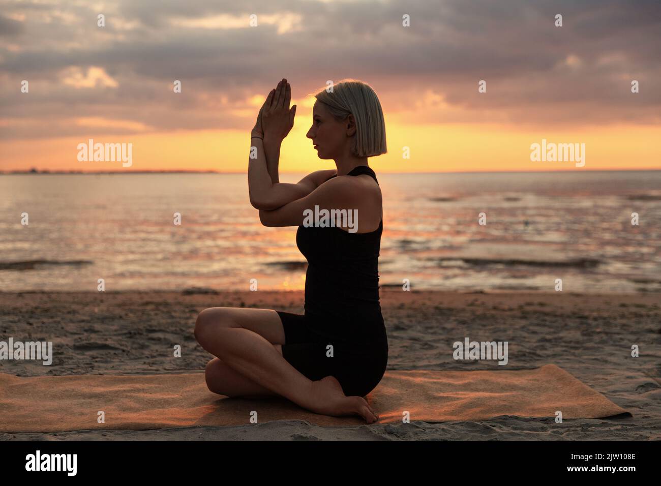 Group of young sporty attractive people in yoga studio, practicing yoga  lesson with instructor, sitting on floor in easy seated eagle yoga pose  Stock Photo - Alamy