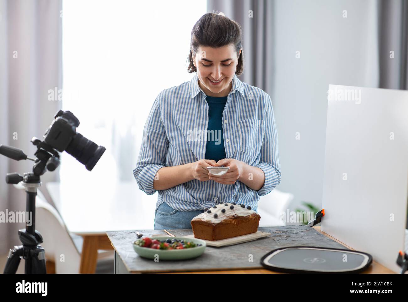 food blogger with camera icing cake in kitchen Stock Photo - Alamy