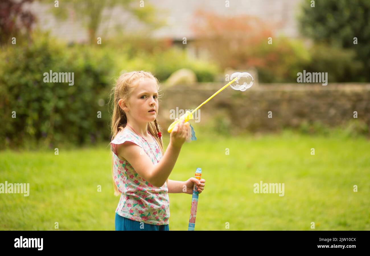 Young girl playing with bubbles in the outdoors on a field. Stock Photo