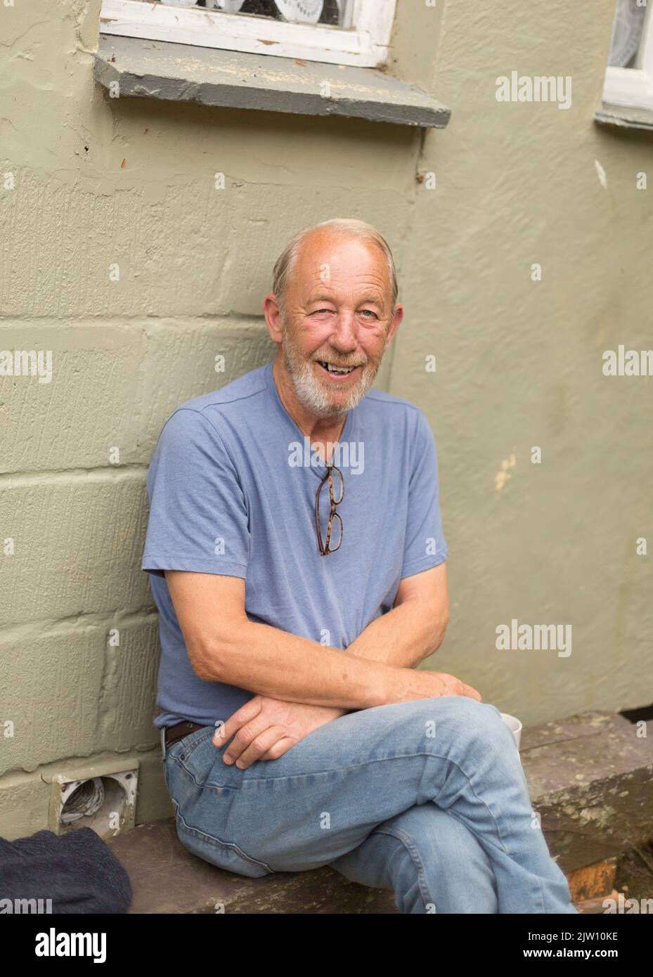 Old caucasian man sits and smiles for the camera. Stock Photo