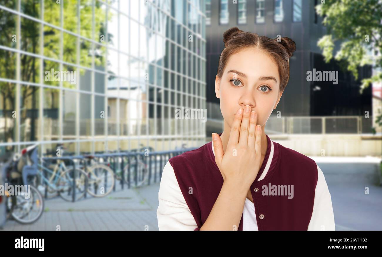 confused teenage girl covering mouth by hand Stock Photo