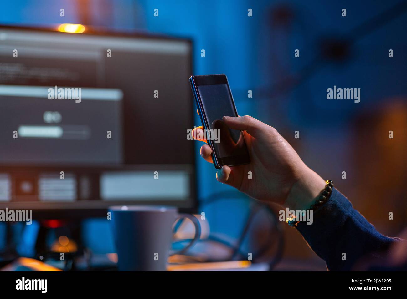 hacker with smartphone and computers in dark room Stock Photo