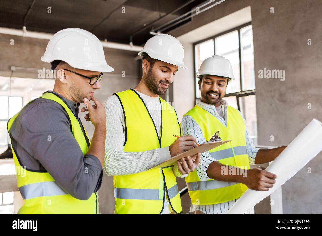 architects in helmets with blueprint at office Stock Photo