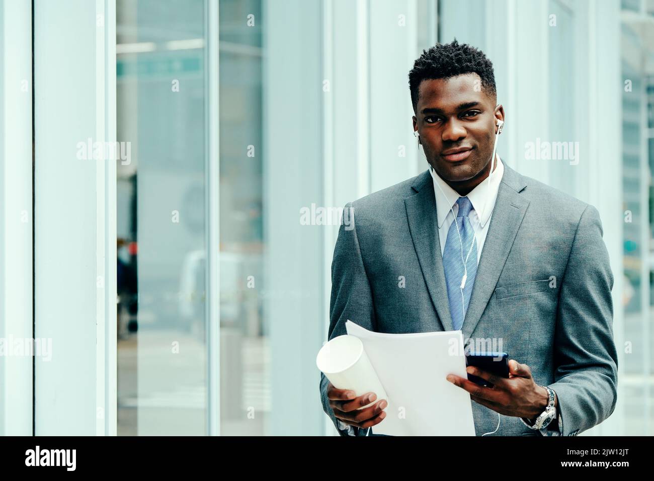 Positive young businessman using smartphone outside wearing suit and ...