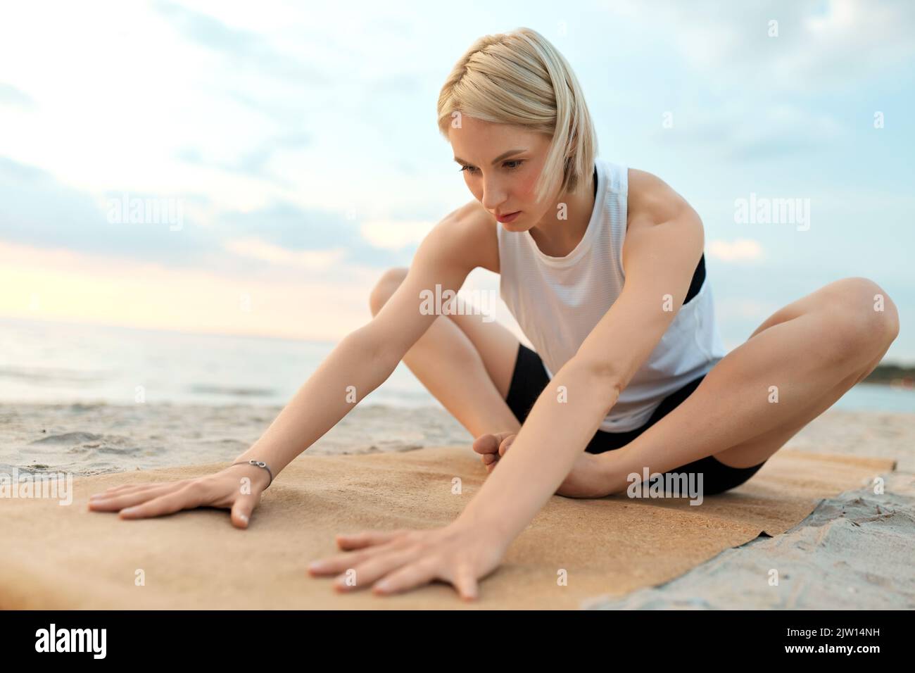 woman doing yoga stretching pose on beach Stock Photo