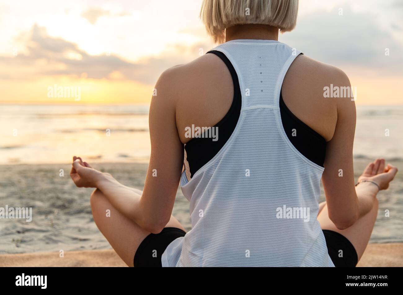 woman meditating in lotus pose on beach Stock Photo - Alamy