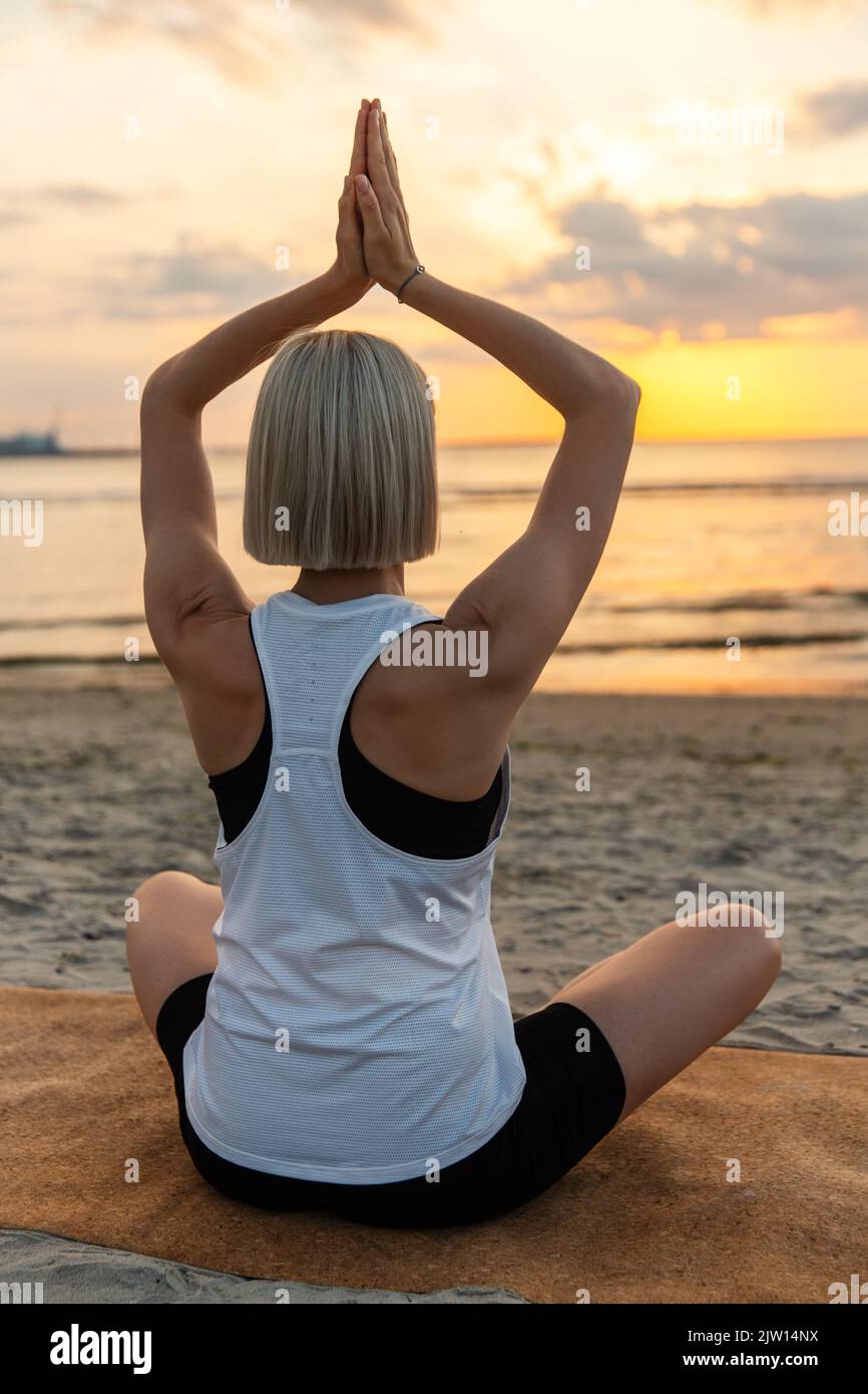 woman meditating in lotus pose on beach Stock Photo - Alamy