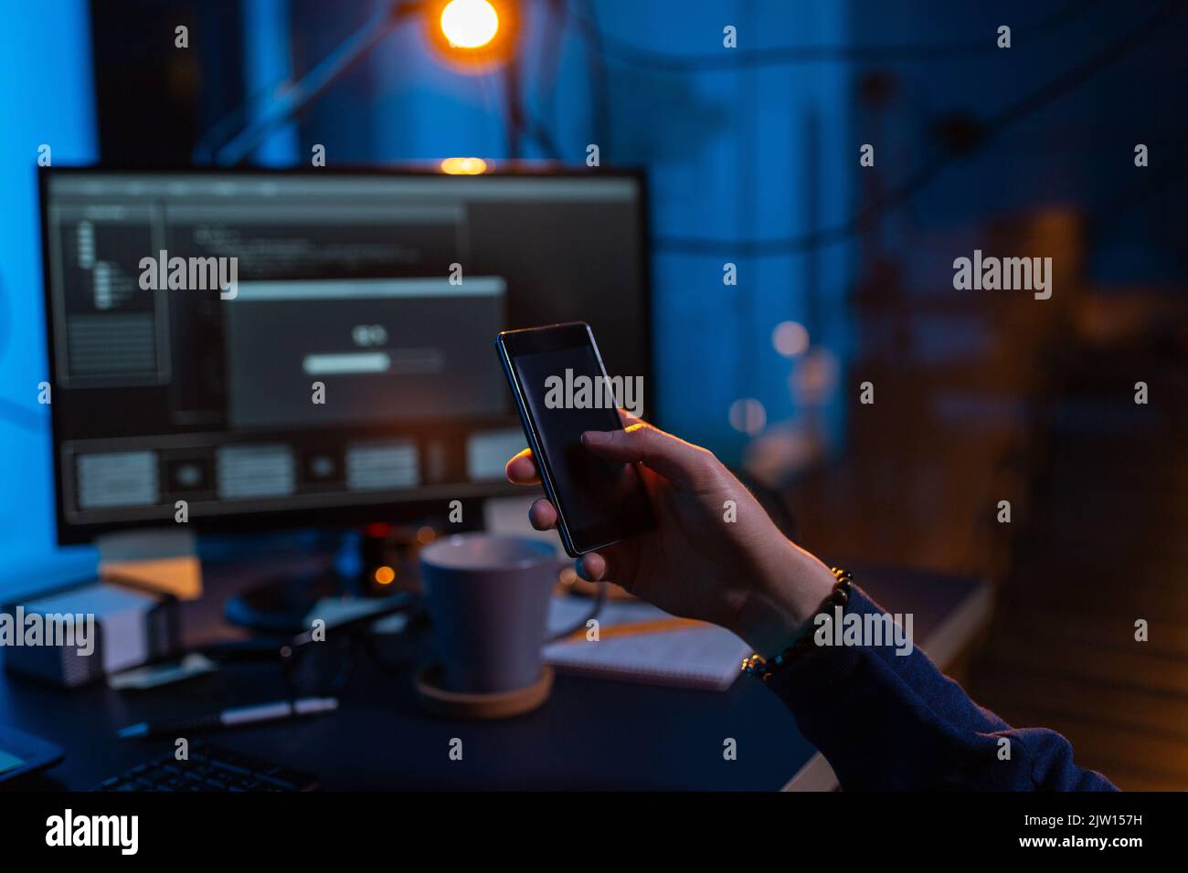 hacker with smartphone and computers in dark room Stock Photo
