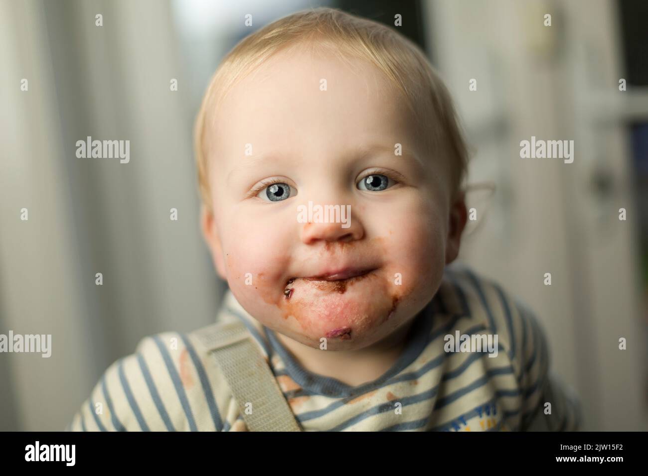 Toddler Caucasian male with a messy mouth from eating ice cream looks