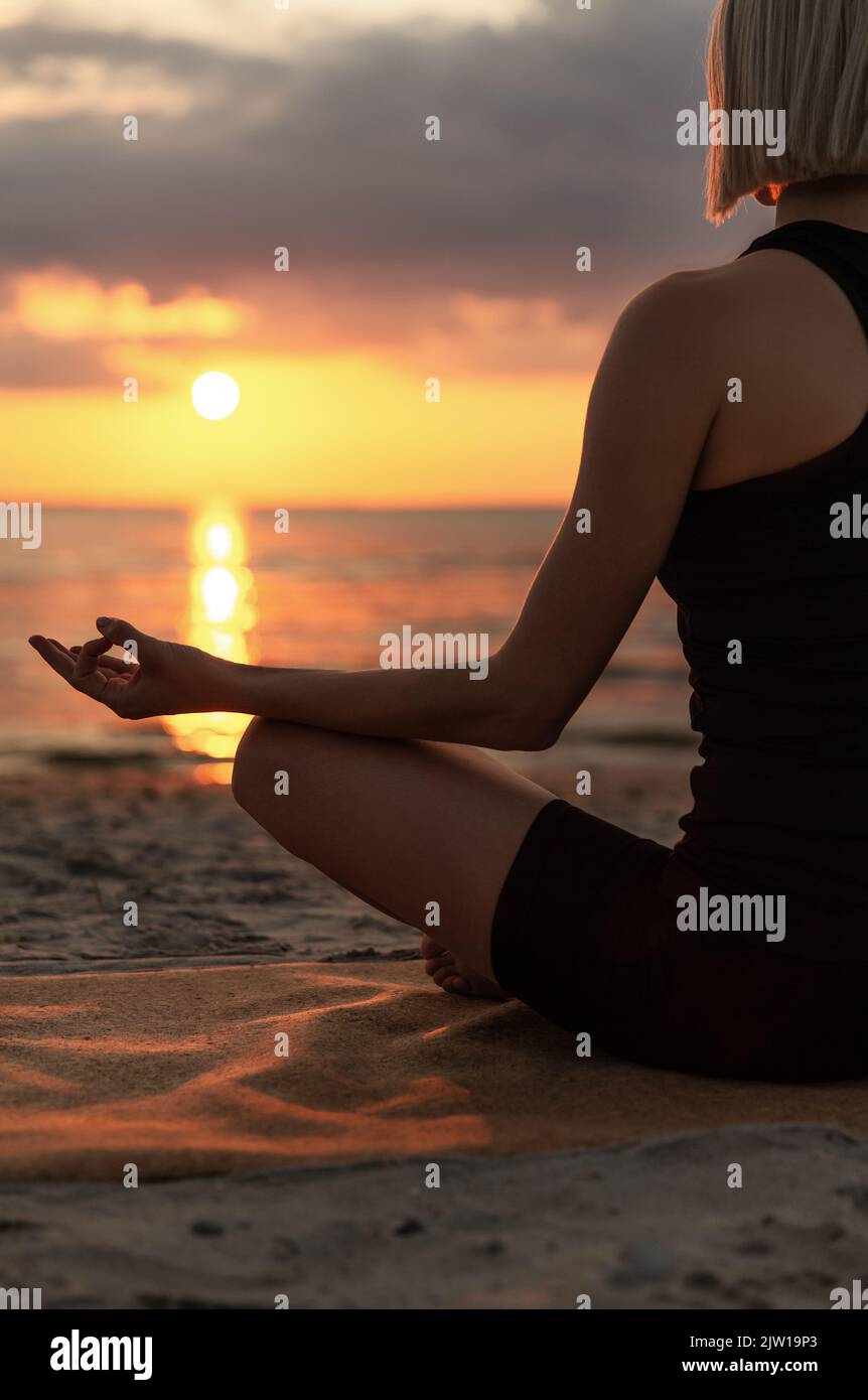 woman meditating in lotus pose on beach Stock Photo - Alamy
