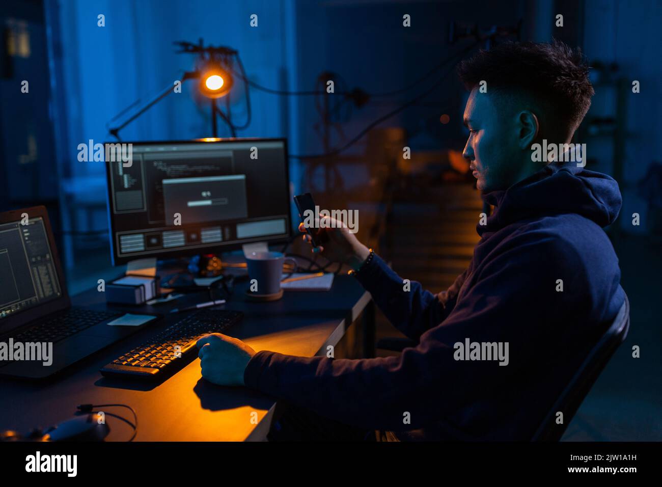 hacker with smartphone and computers in dark room Stock Photo - Alamy