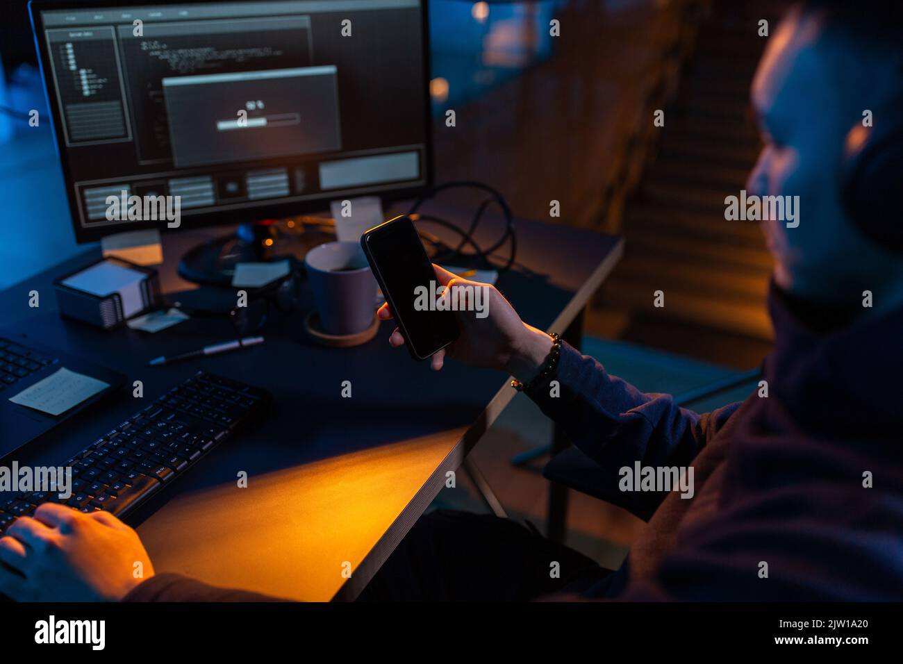 hacker with smartphone and computers in dark room Stock Photo