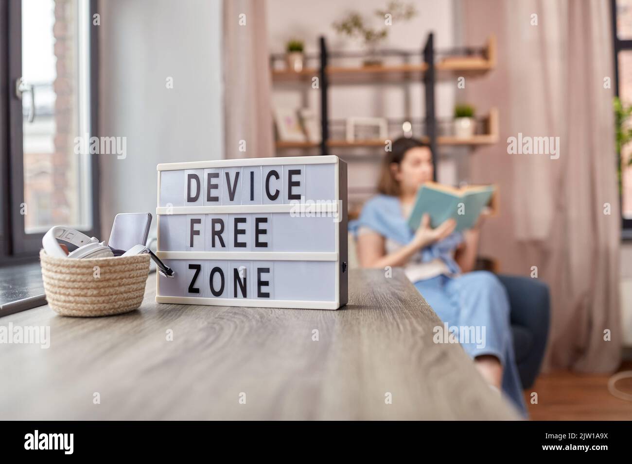 gadgets at device free zone and woman reading book Stock Photo Alamy