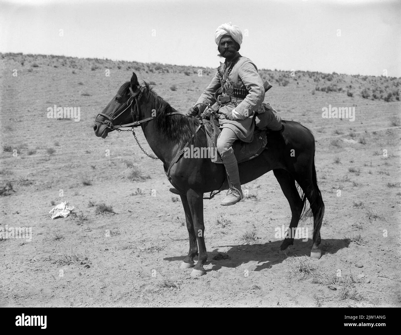 AJAXNETPHOTO. 1919-1920S (APPROX). INDIA. NORTHWEST FRONTIER. - ARMED RIDER - A MOUNTED ARMED RIDER, POSSIBLY WAZIRISTAN MILITIA IN TRADITIONAL ATTIRE, WEARING AMMUNITION BELTS WITH RIFLE SLUNG ACROSS BACK, POSES FOR THE CAMERA. PHOTOGRAPHER:UNKNOWN © DIGITAL IMAGE COPYRIGHT AJAX VINTAGE PICTURE LIBRARY SOURCE: AJAX VINTAGE PICTURE LIBRARY COLLECTION REF:1920 6 2 Stock Photo