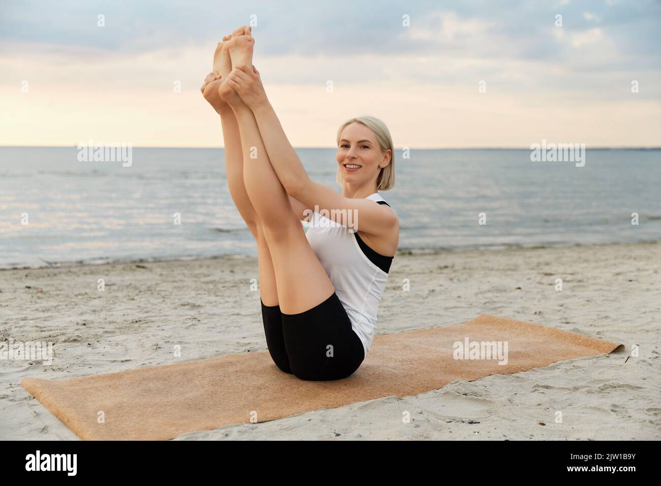woman doing yoga boat pose on beach Stock Photo - Alamy