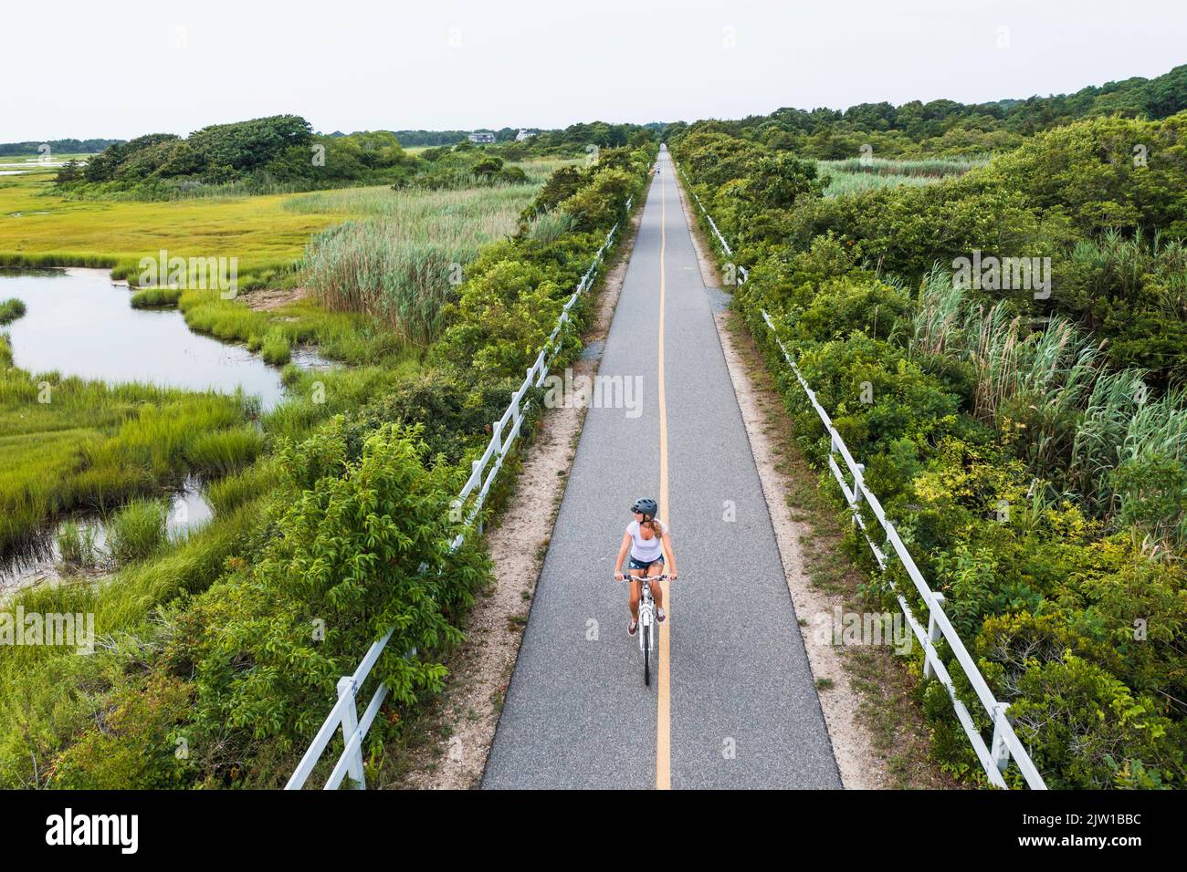 Aerial drone of Woman biking through Cape Cod Marshes bike path Stock Photo