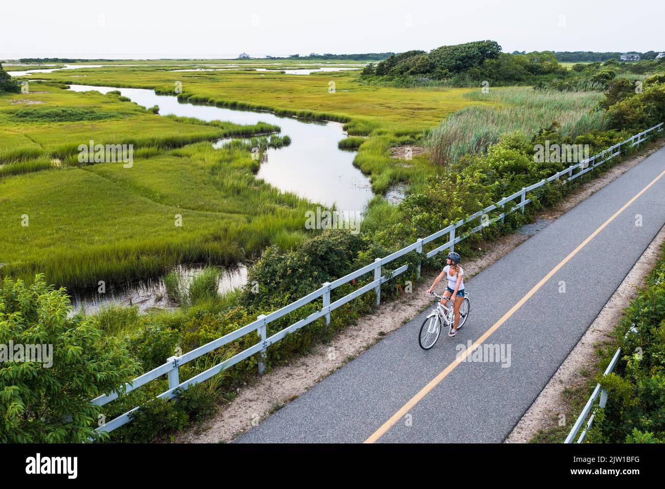 Aerial drone of Woman biking through Cape Cod Marshes bike path Stock Photo