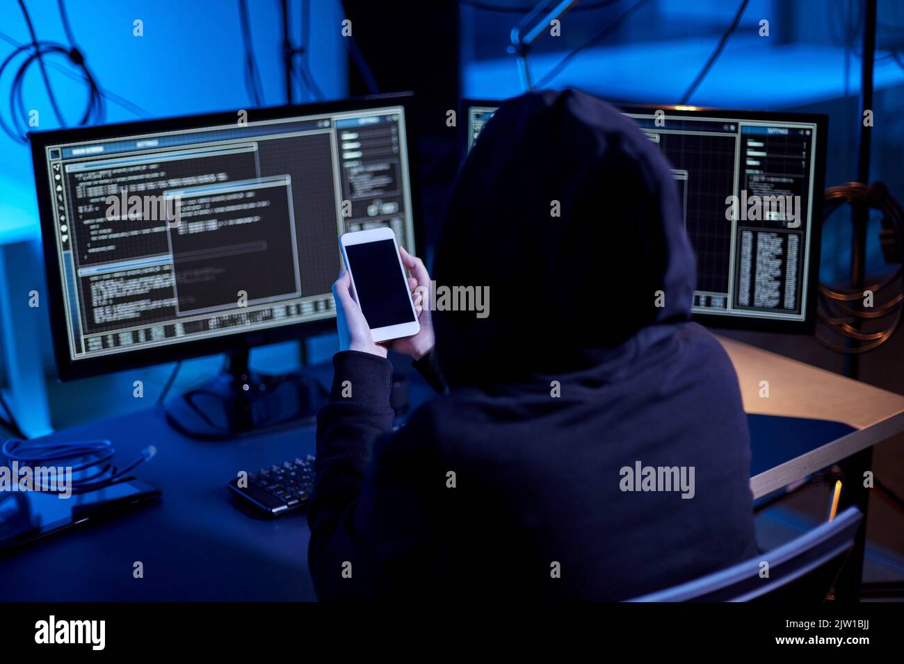 hacker with smartphone and computers in dark room Stock Photo - Alamy