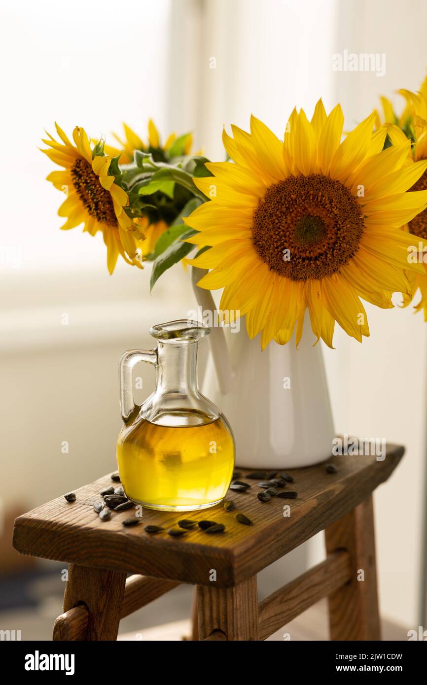 Sunflower oil in a glass jug with a bouquet of sunflowers Stock Photo