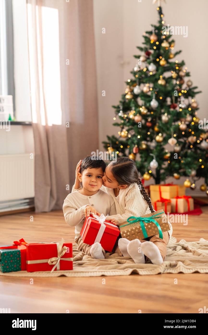 girl kissing brother with christmas gifts at home Stock Photo