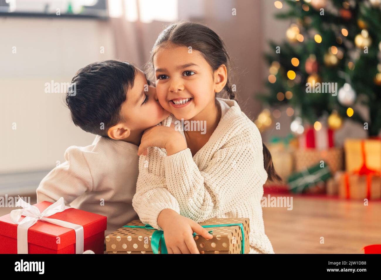 boy kissing sister with christmas gifts at home Stock Photo