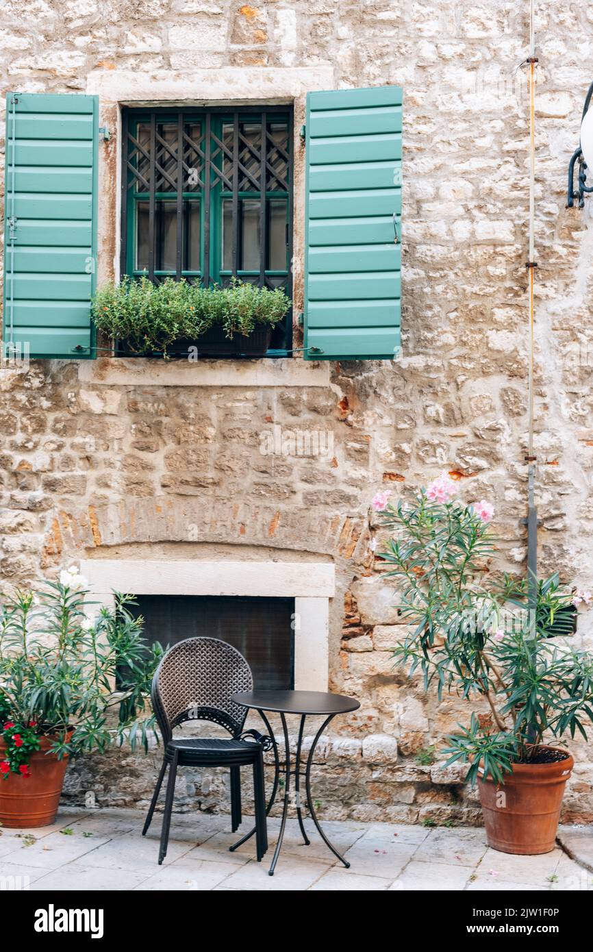 Window with green shutters and table of the street cafe in Sibenik, Croatia Stock Photo