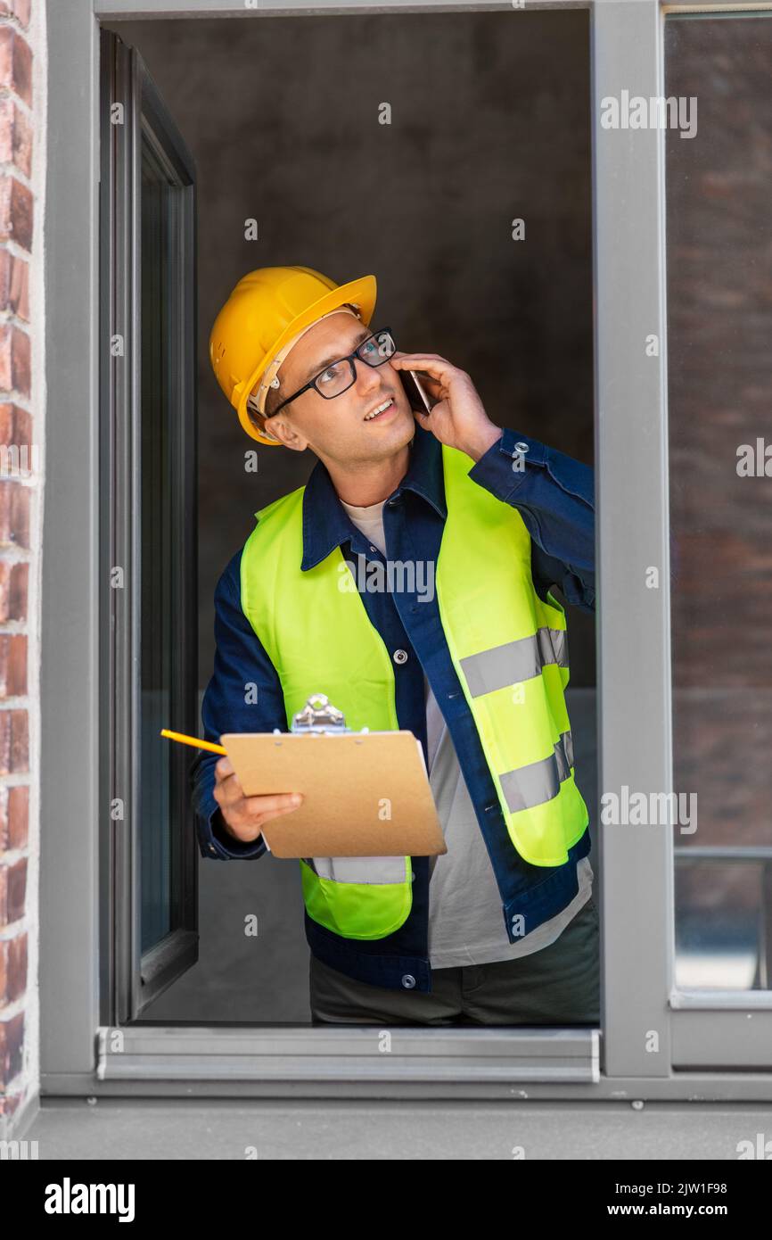 builder with clipboard and calling on smartphone Stock Photo