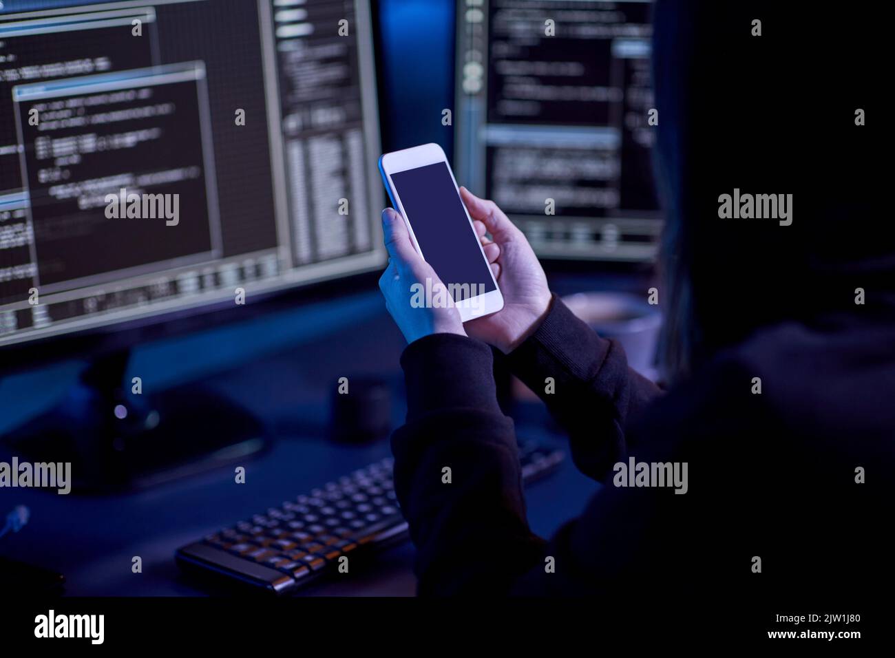 hacker with smartphone and computers in dark room Stock Photo