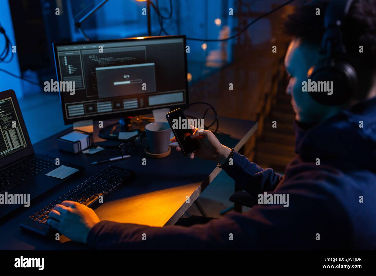 hacker with smartphone and computers in dark room Stock Photo - Alamy