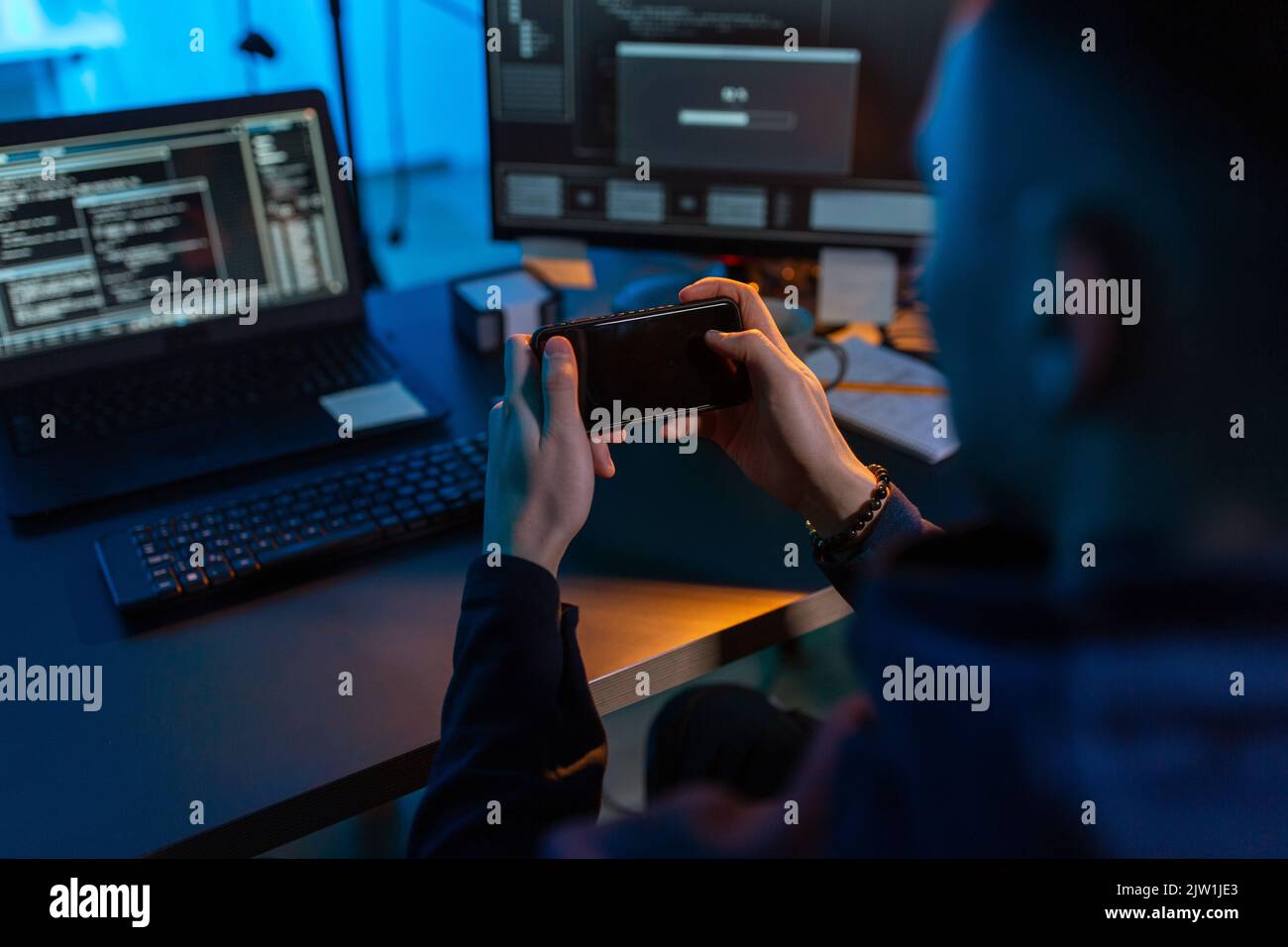 hacker with smartphone and computers in dark room Stock Photo - Alamy